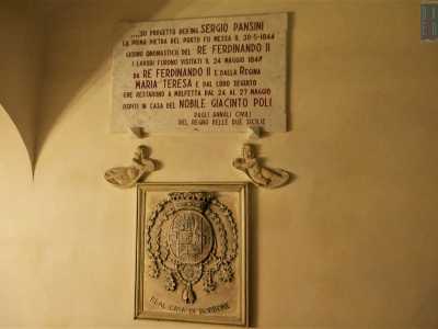 Dopo aver varcato il portone in legno, ci ritroviamo in un androne dove una targa celebra i giorni del maggio 1847 in cui il re Ferdinando II di Borbone e la regina Maria Teresa soggiornarono proprio qui, ospiti di Giacinto Poli
